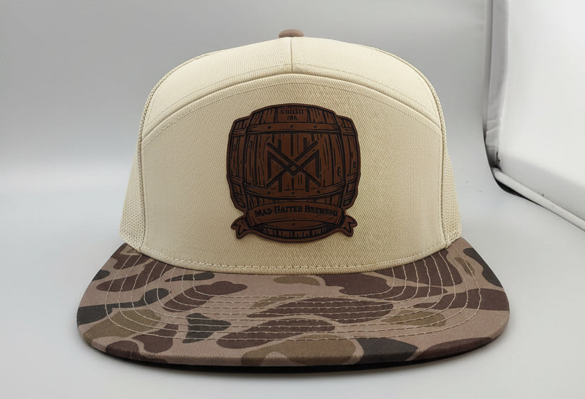 Beige cap with camouflage brim and logo on a white surface
